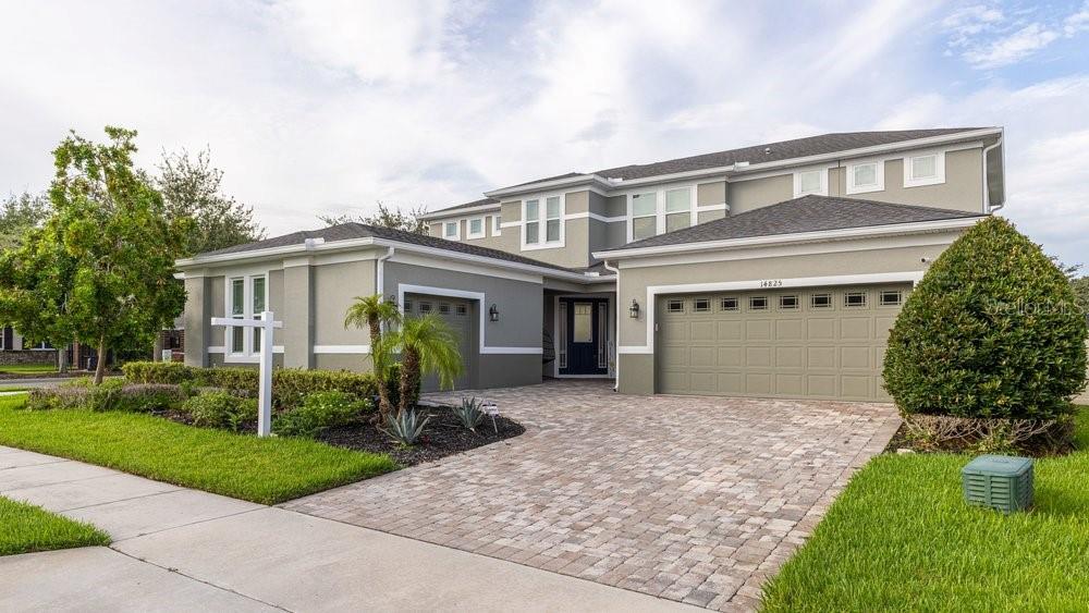 A two-story suburban house with a light-colored exterior, a paved driveway, and a garage — 14825 ELLINGSWORTH LANE, WINTER GARDEN, FL