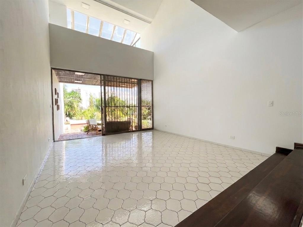 A living room features white hexagonal tile floors, high ceilings, and a sliding glass door — I 25 VILLA CAPARRA NOR, GUAYNABO, PR