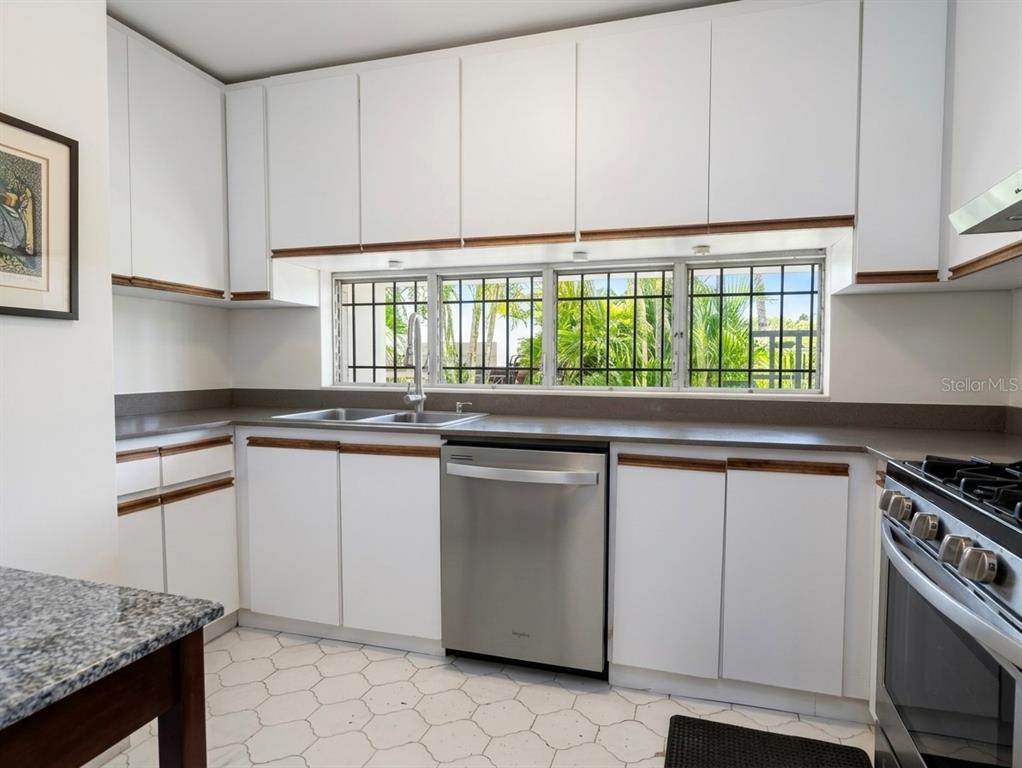 A kitchen features white cabinets with wood trim, stainless steel appliances, and a window view — I 25 VILLA CAPARRA NOR, GUAYNABO, PR