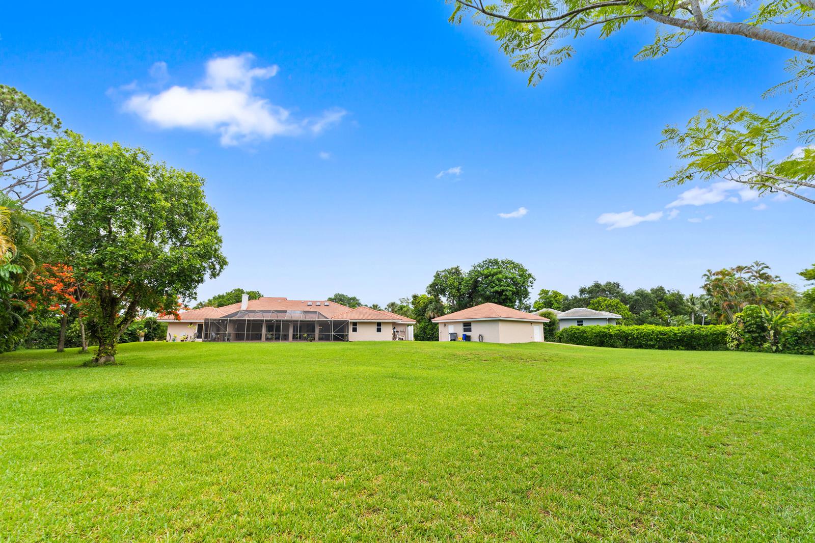 A large grassy backyard features a single-story house with a screened-in patio and detached garage — 22829 Horse Shoe Way, Boca Raton FL 33428, BOCA RATON, FL