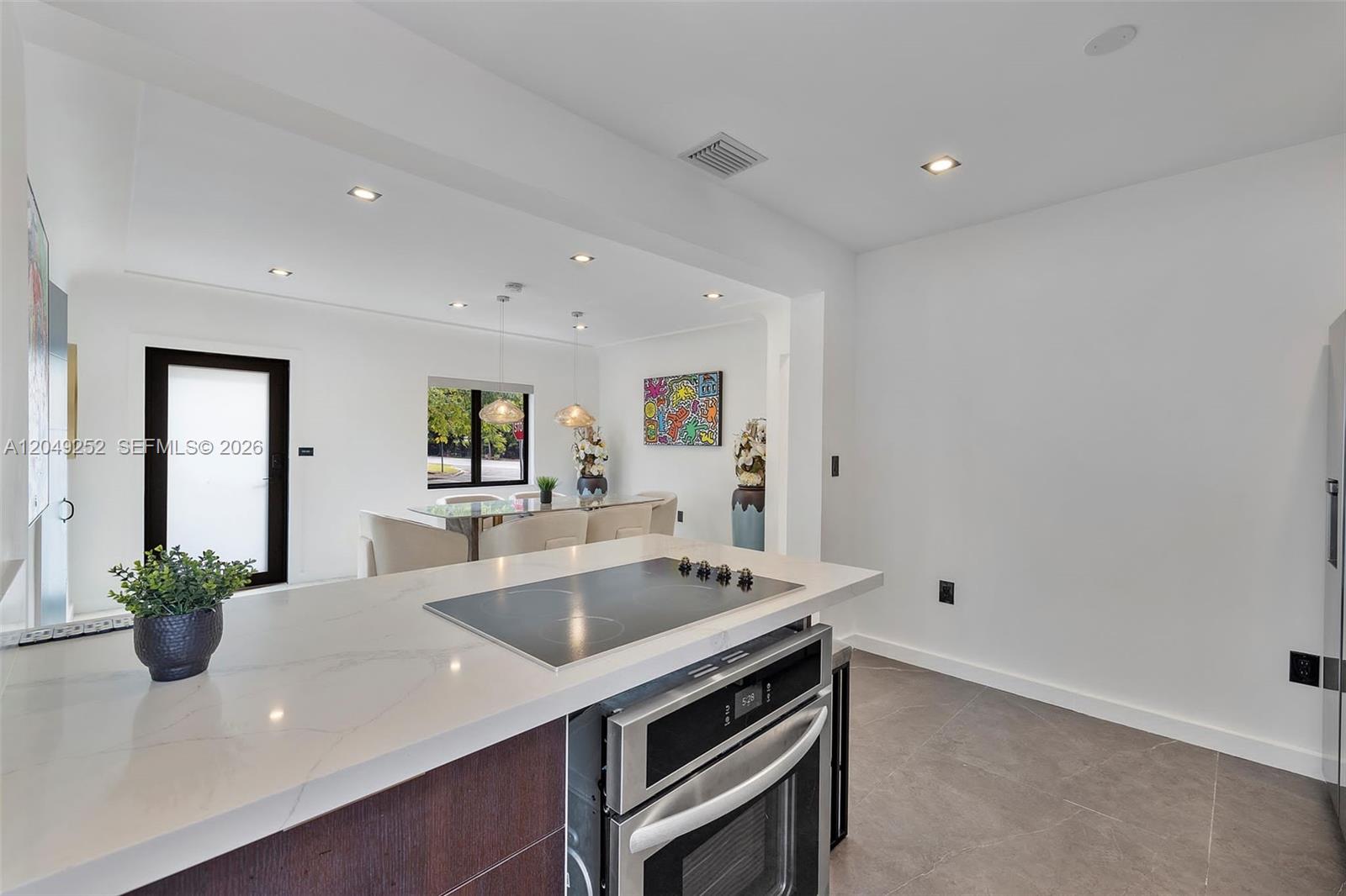 A modern kitchen features a white quartz island with a cooktop and stainless steel oven — 501 NW 46th St # 0, Miami FL 33127, MIAMI, FL