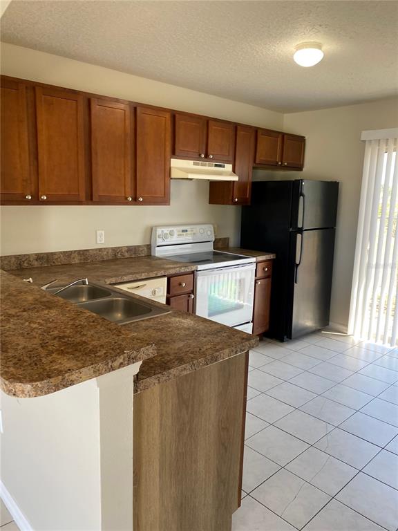 An open-concept living area features light-colored tile flooring and an arched entryway to the kitchen — 1830 2ND STREET NW UNIT A, WINTER HAVEN, FL