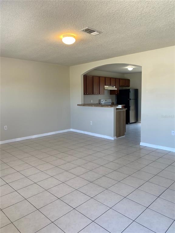 A spacious living area features light-colored tile flooring, an arched entryway, and a breakfast bar — 1830 2ND STREET NW UNIT A, WINTER HAVEN, FL