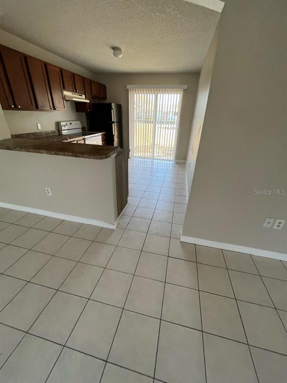 An empty bedroom features light-colored walls, wood-look flooring, a window with blinds, and a light — 1830 2ND STREET NW UNIT A, WINTER HAVEN, FL
