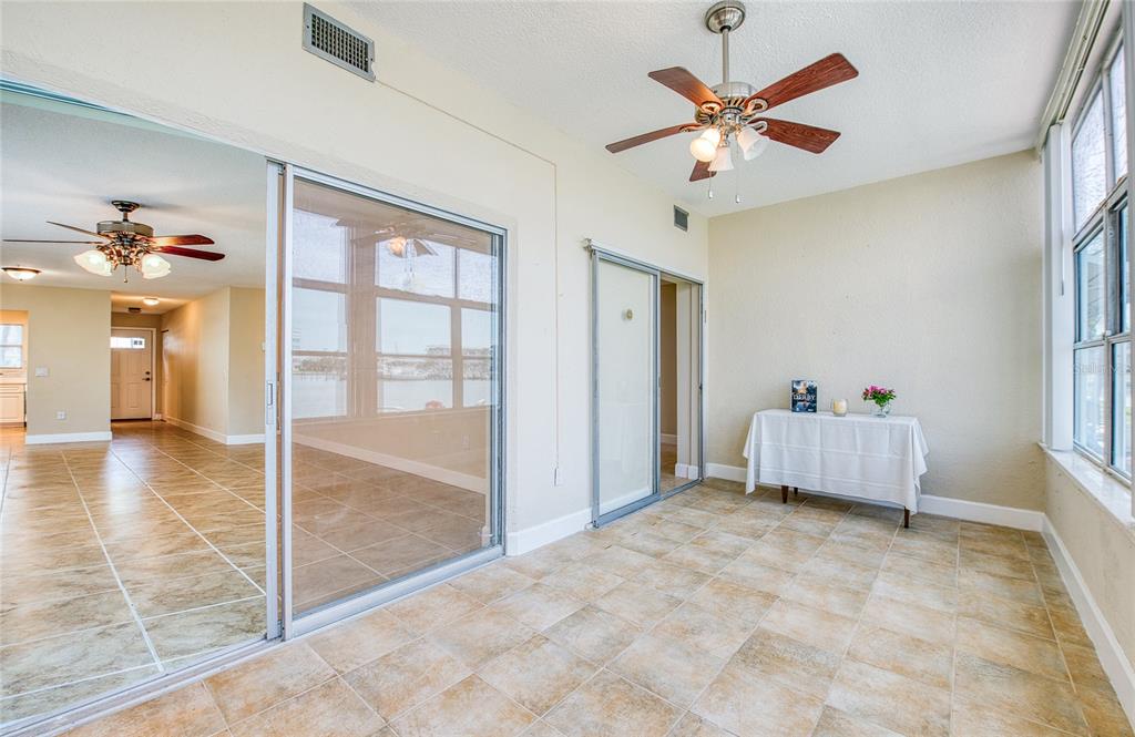 A sunroom with tile flooring, a ceiling fan, and sliding glass doors overlooking the water — 5940 30TH AVENUE S UNIT 115, GULFPORT, FL