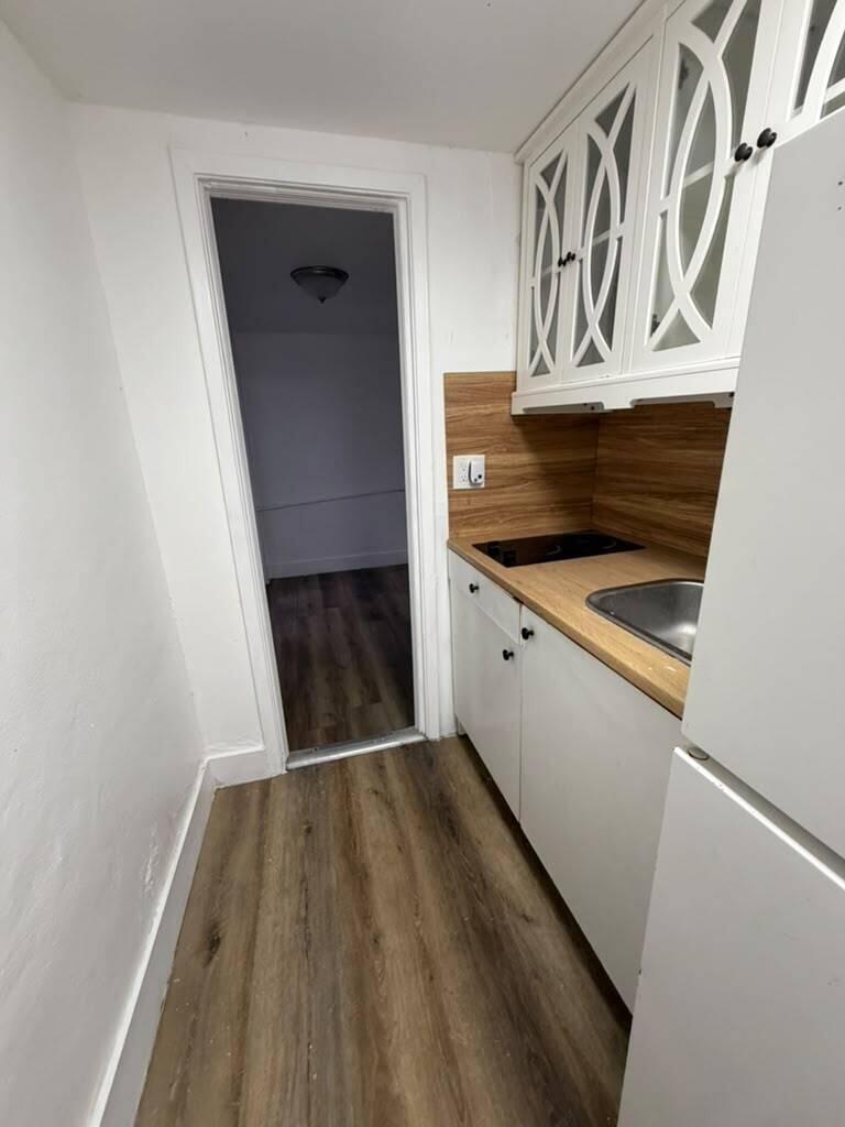 A small kitchen features white cabinets, a wood-look countertop, and wood-patterned flooring — 2137 NW 1st Terrace, FL 33125, FL