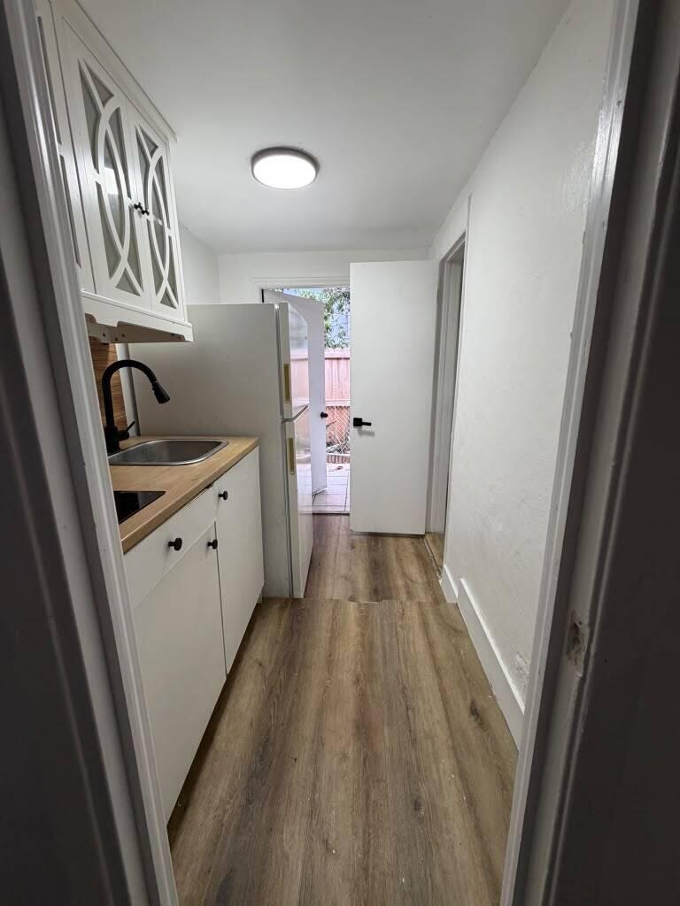 A narrow kitchen features white cabinets, wood countertops, a stainless steel sink, and wood flooring — 2137 NW 1st Terrace, FL 33125, FL