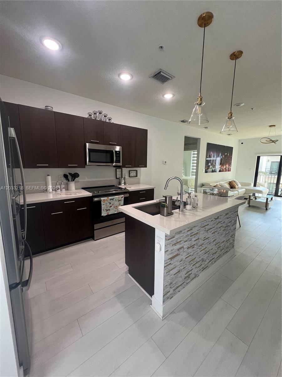 A modern kitchen features dark wood cabinets, white countertops, and a stone-tiled island — 4670 NW 84th Ave # 32, Doral FL 33166, DORAL, FL