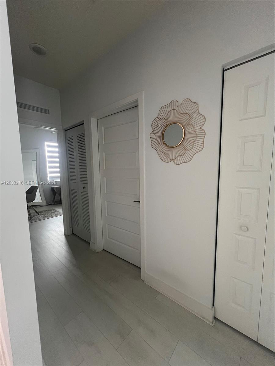 A hallway features light wood-look flooring, white doors, and a decorative circular wall mirror — 4670 NW 84th Ave # 32, Doral FL 33166, DORAL, FL