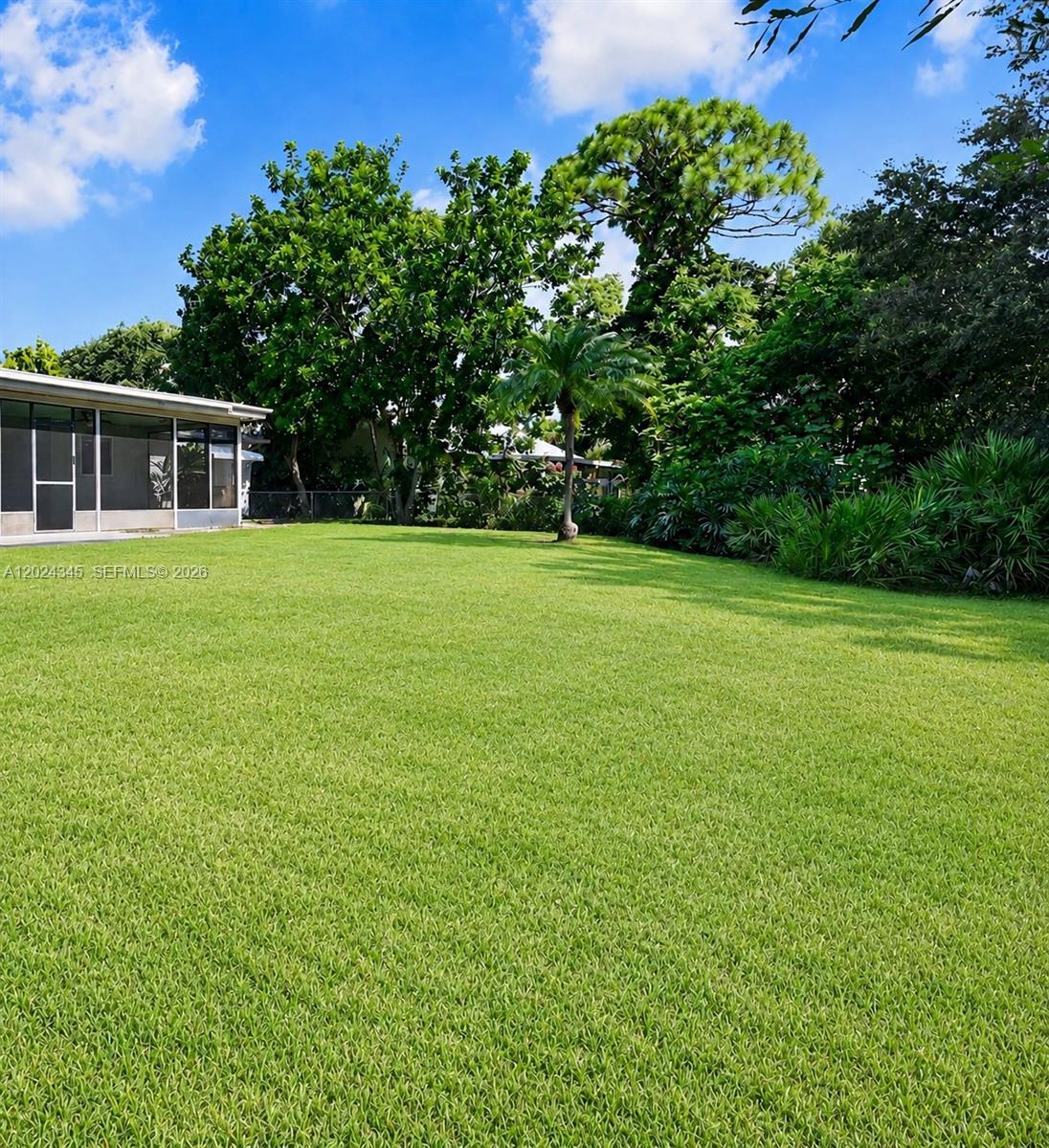 A large, grassy backyard features a screened-in patio and several mature trees — 112 SE Vin Rose Cir, Palm Bay FL 32909, PALM BAY, FL