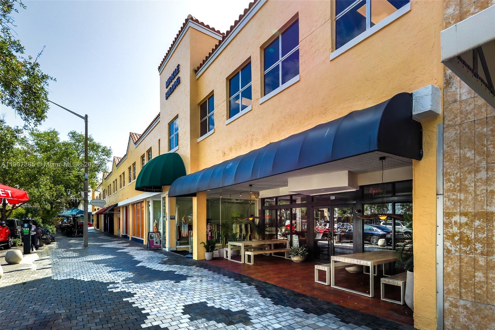 A yellow commercial building features a black awning over a storefront with outdoor seating — 220 Miracle Mile # B236, Coral Gables FL 33134, CORAL GABLES, FL