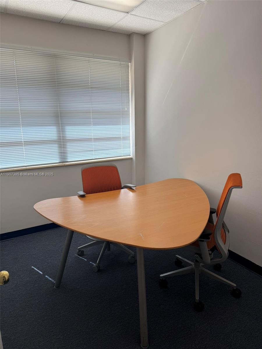 An office space features a triangular wooden desk and two orange chairs on blue carpet — 220 Miracle Mile # B236, Coral Gables FL 33134, CORAL GABLES, FL
