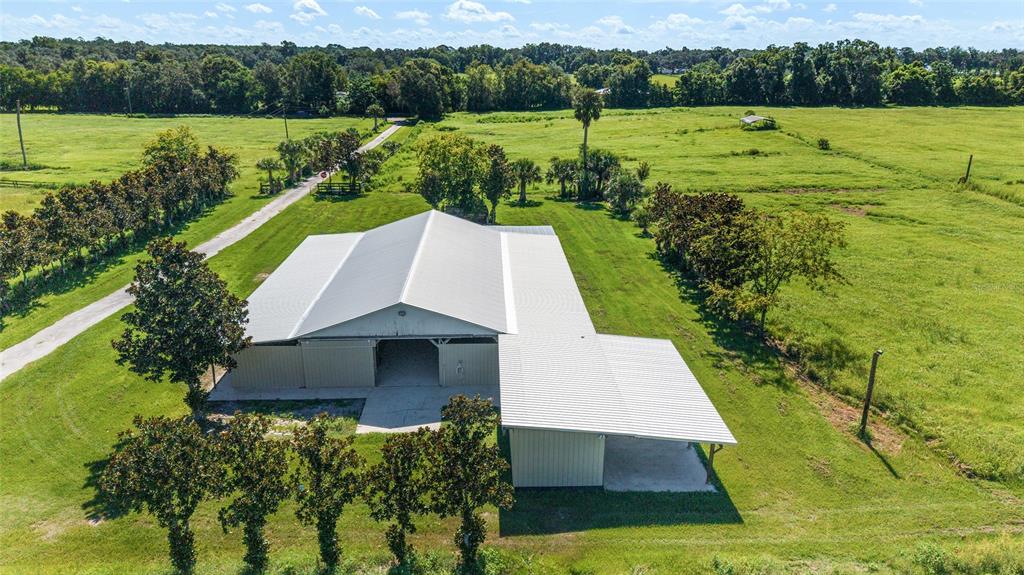 An aerial view shows a large metal barn with a side carport on a grassy lot — 5800 SE 145TH STREET, SUMMERFIELD, FL