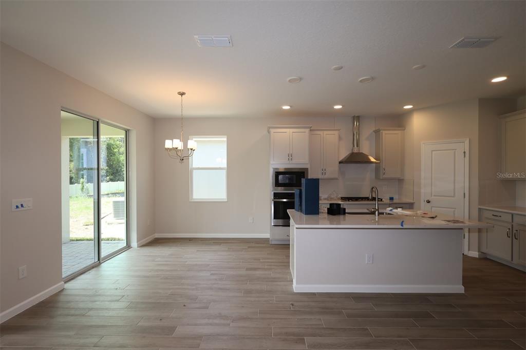 A kitchen and dining area with white cabinets, a center island, and wood-look tile floors — 1302 HYDE STREET, ST CLOUD, FL