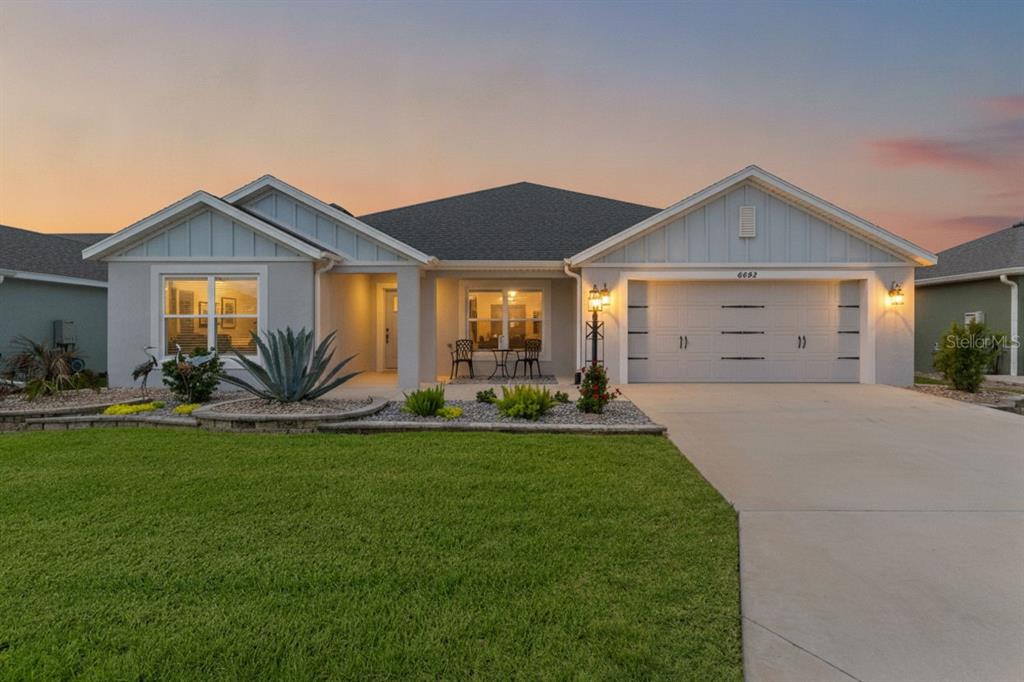 A single-story house with a light gray exterior, a two-car garage, and a landscaped front yard — 6692 NEWELL LOOP, THE VILLAGES, FL