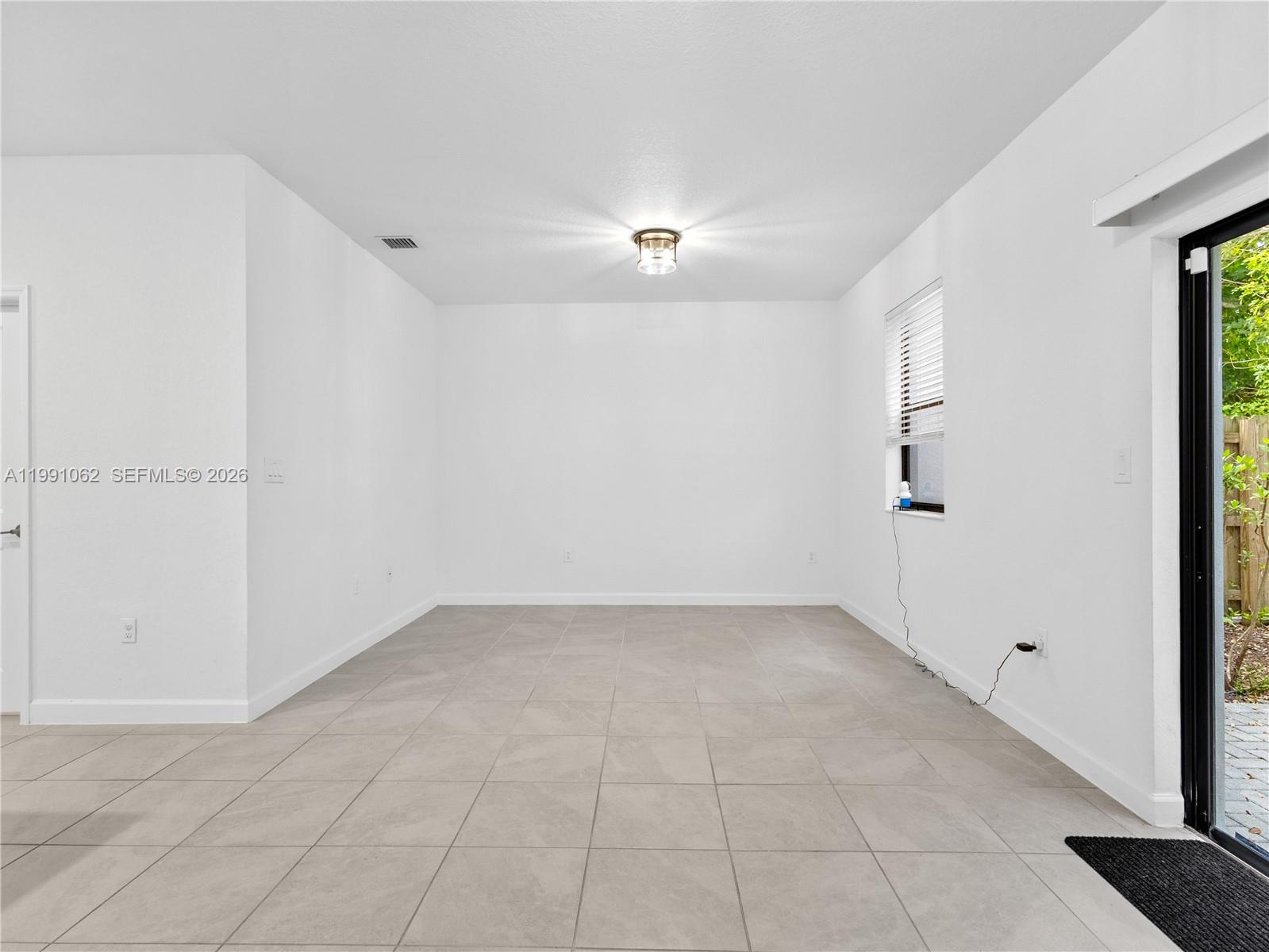 An empty room features white walls, light tile flooring, a ceiling light, and a sliding door — 28562 SW 134th Ct, Miami FL 33033, MIAMI, FL