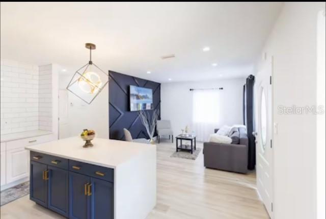 A kitchen island with blue cabinets sits in front of a living area with dark accents — 7712 DELEUIL AVENUE, TAMPA, FL