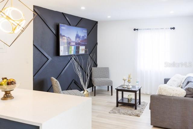 A living room features a black geometric accent wall with a mounted television and furniture — 7712 DELEUIL AVENUE, TAMPA, FL
