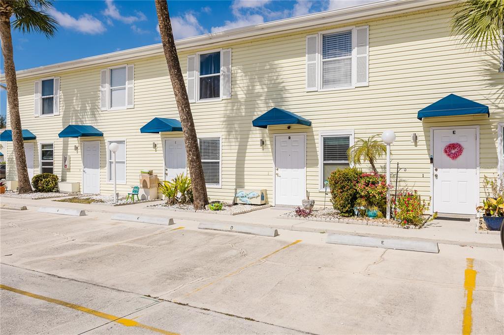 A row of yellow townhouses with blue awnings and assigned parking spaces in front — 26282 RAMPART BOULEVARD UNIT 204, PUNTA GORDA, FL