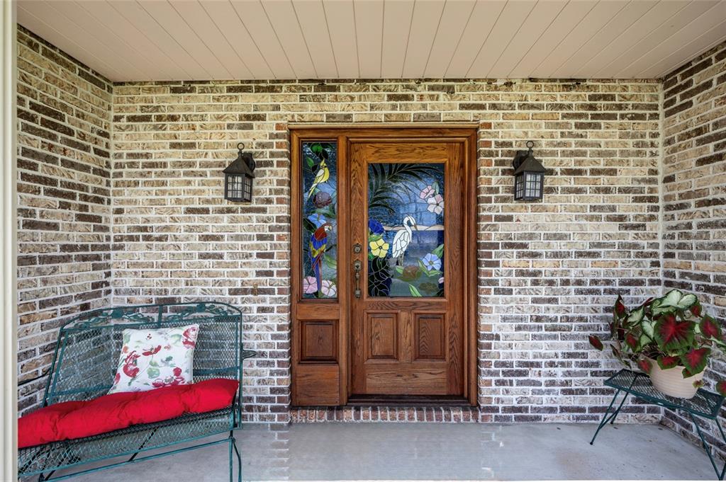 A front porch features a brick exterior, a wooden door with stained glass, and metal furniture — 29 WOOD HAVEN DRIVE, PALM COAST, FL