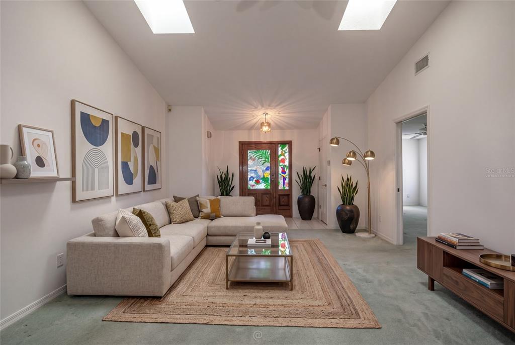 A living room features a beige sectional sofa, a glass coffee table, and a stained-glass door — 29 WOOD HAVEN DRIVE, PALM COAST, FL