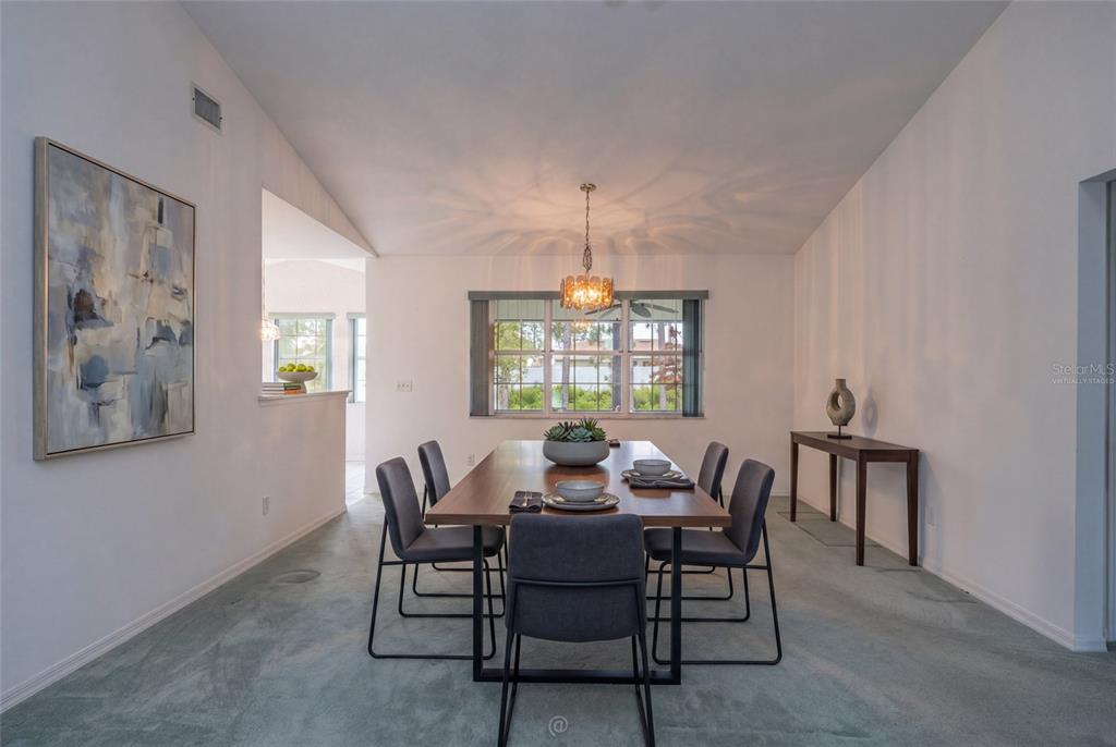 A dining room features a wooden table with six chairs, a chandelier, and carpeted flooring — 29 WOOD HAVEN DRIVE, PALM COAST, FL