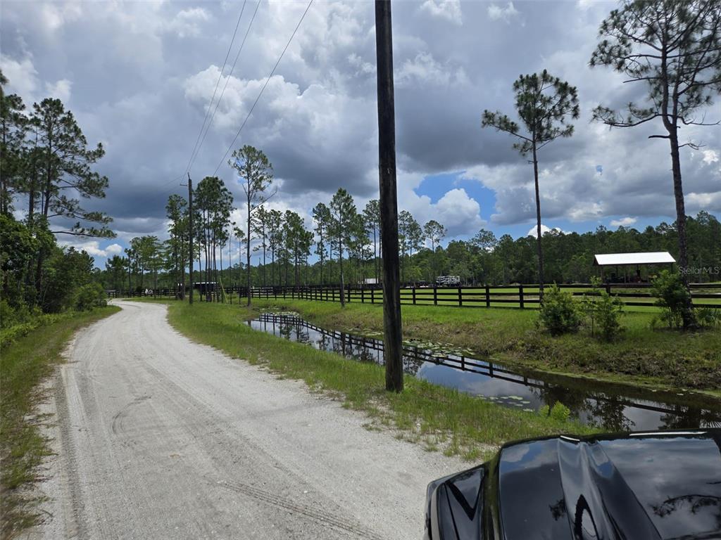 A gravel road runs alongside a drainage ditch and a fenced pasture with trees — 1135 OMEGA RANCH ROAD UNIT 4&5, NEW SMYRNA BEACH, FL