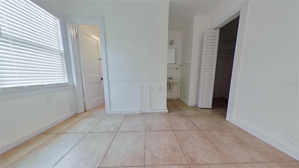 A room with tiled flooring, a window with blinds, two doorways, and a small sink area — 327 NW 15TH TERRACE, GAINESVILLE, FL