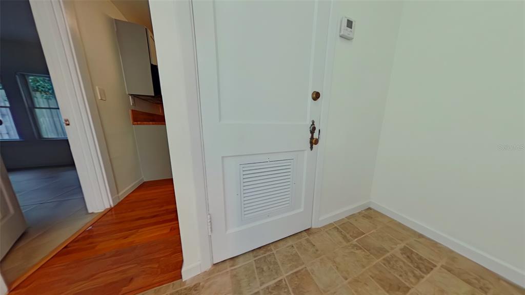 A white door with a louvered vent panel stands in a room with tiled flooring — 327 NW 15TH TERRACE, GAINESVILLE, FL