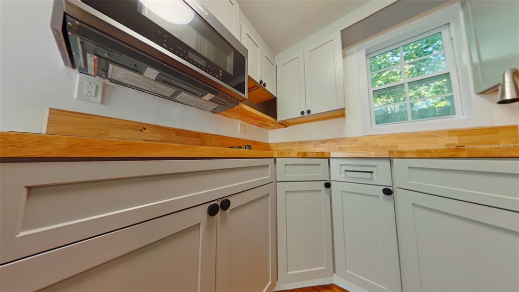 A kitchen features light gray cabinets, a wood countertop, and an over-the-range microwave — 327 NW 15TH TERRACE, GAINESVILLE, FL