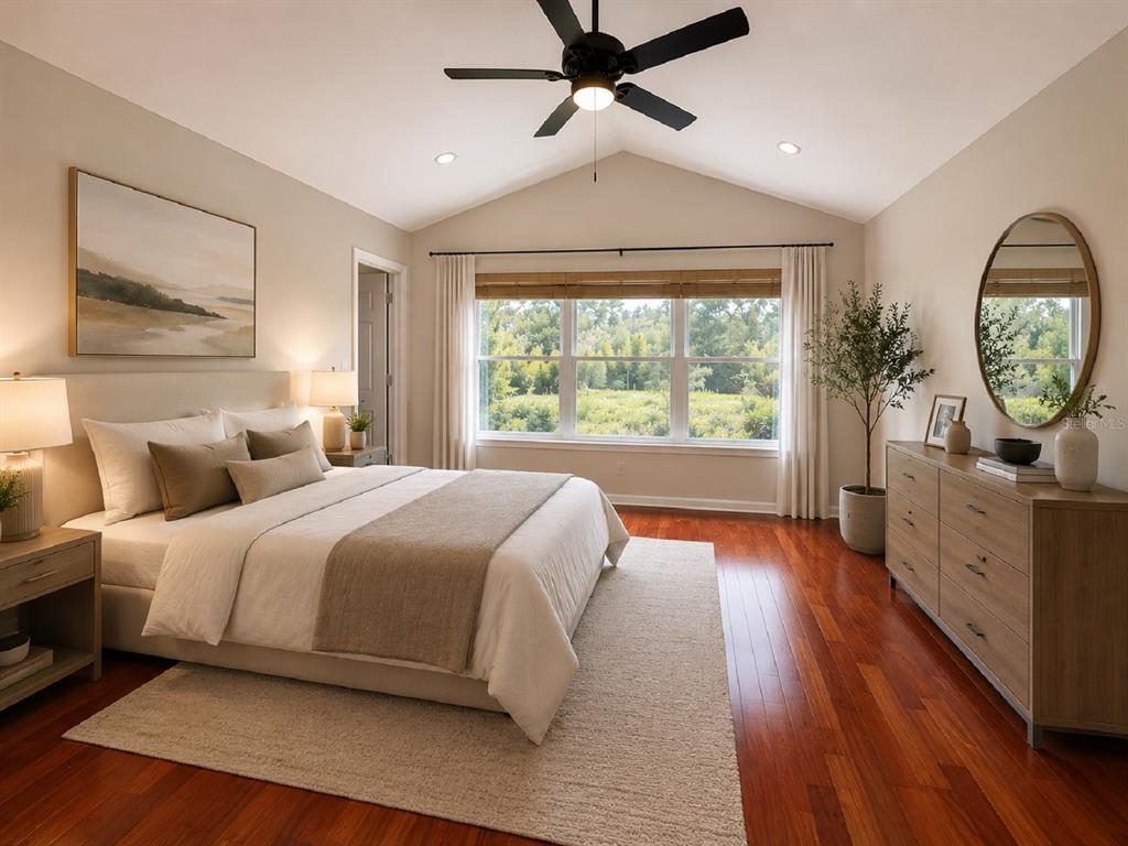 A bedroom with a vaulted ceiling, hardwood floors, a bed, and a dresser with a mirror — 26613 CASTLEVIEW WAY, WESLEY CHAPEL, FL