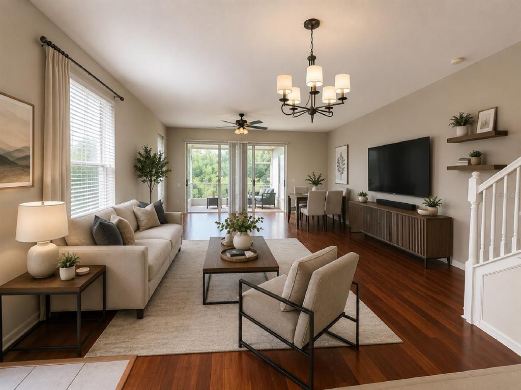 A living room with hardwood floors, a sofa, an armchair, and a television on a console — 26613 CASTLEVIEW WAY, WESLEY CHAPEL, FL