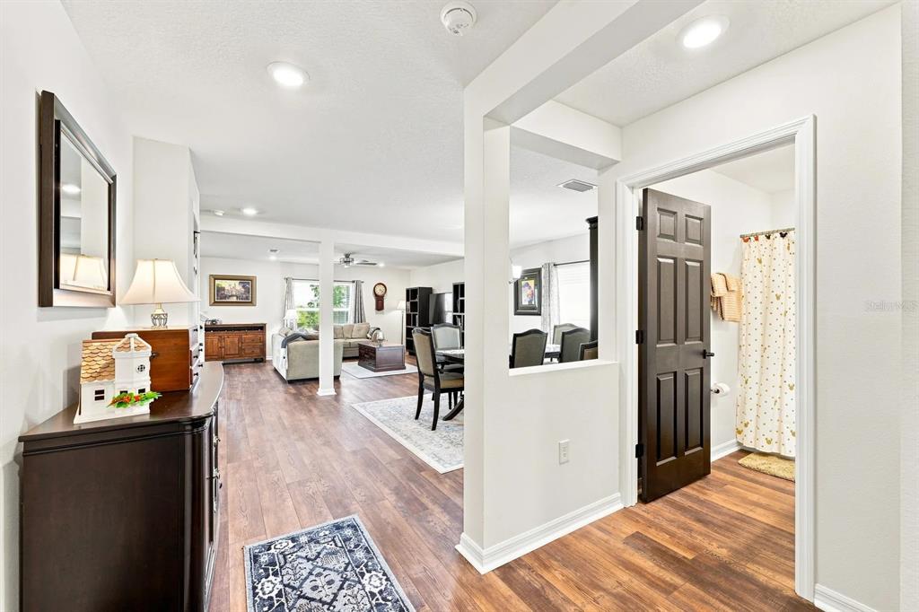 A view from a hallway looking into an open-concept living and dining area with wood flooring — 455 OVERPOOL AVENUE, DAVENPORT, FL