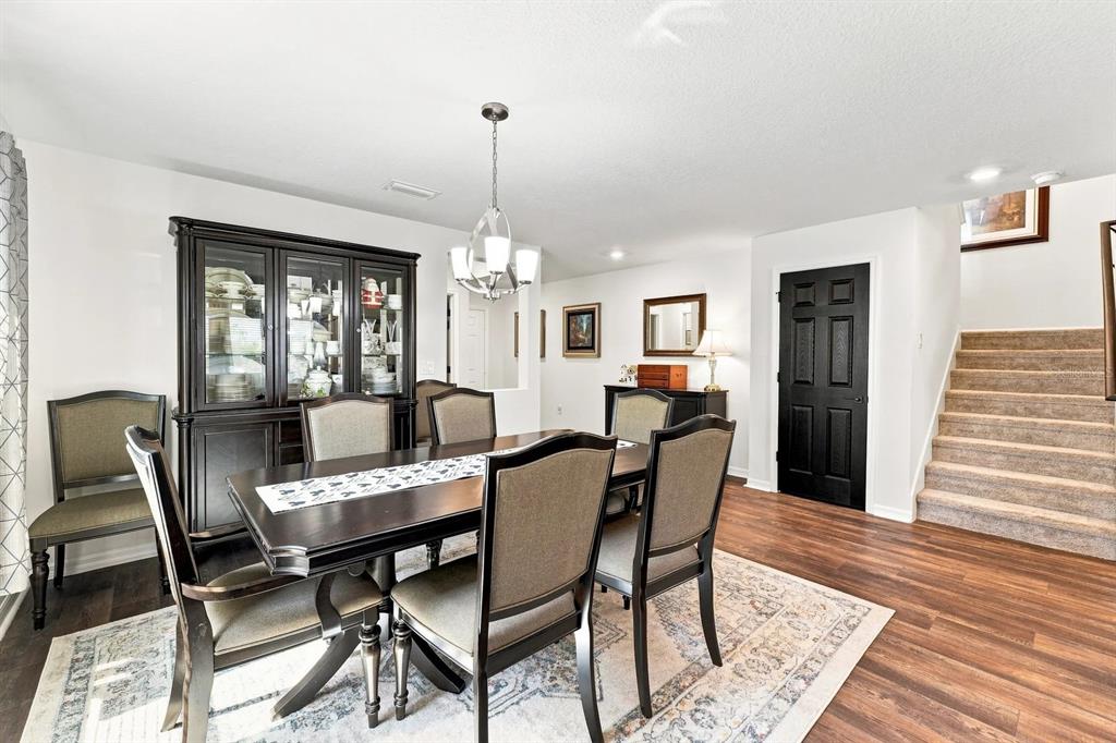 A dining room features a dark wood table and hutch, carpeted stairs, and black doors — 455 OVERPOOL AVENUE, DAVENPORT, FL