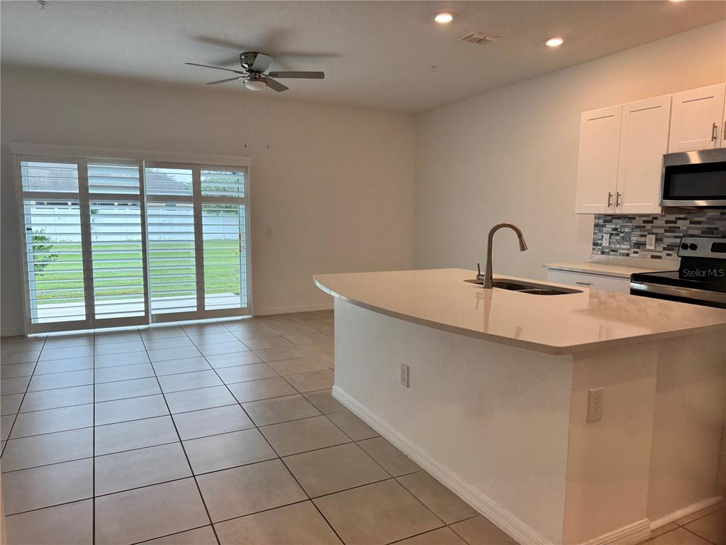 A kitchen with a white island, light countertops, and sliding glass doors leading outside — 4461 ARLINGTON AVENUE, ST CLOUD, FL