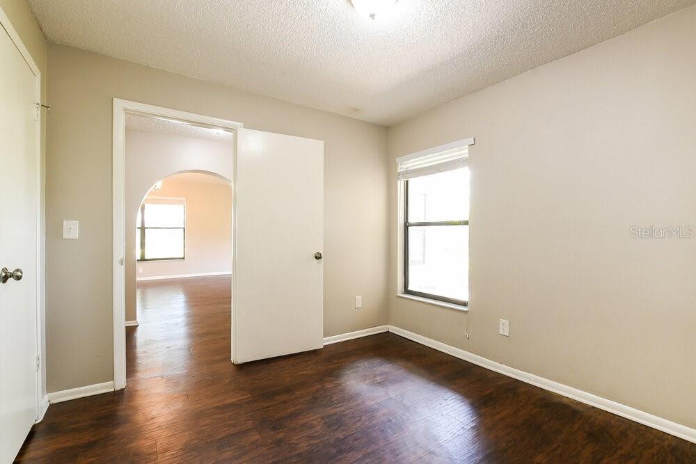 An empty bedroom features light-colored walls, dark wood-look flooring, and a window with blinds — 534 S SUNDANCE DRIVE, LAKE MARY, FL