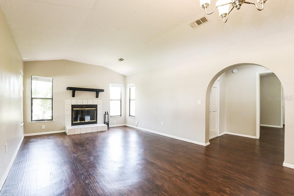 A living room features dark wood-look flooring, a white fireplace, and an arched doorway — 534 S SUNDANCE DRIVE, LAKE MARY, FL