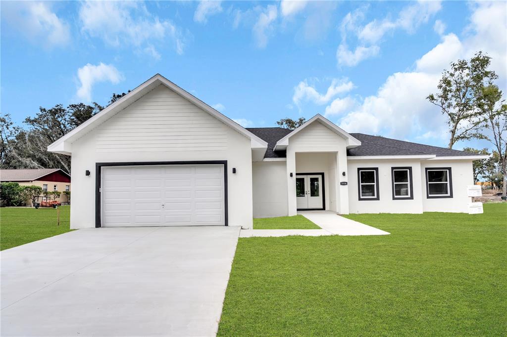 A white single-story house with a two-car garage and a dark shingled roof — 5530 BELL, ZEPHYRHILLS, FL