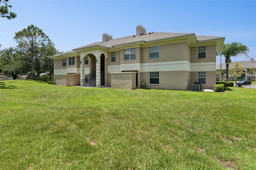 A two-story apartment building exterior features tan stucco walls, a shingled roof, and green lawn — 1502 EAGLE POND DRIVE UNIT 15, WINTER HAVEN, FL