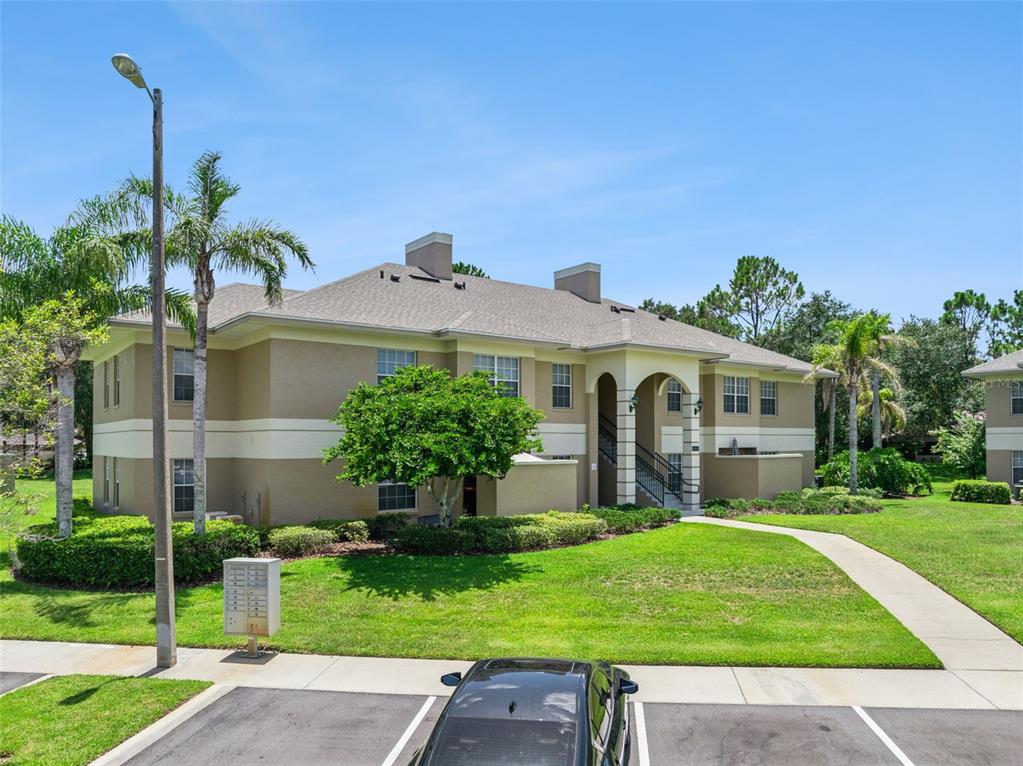 A two-story apartment building with a tan exterior, a shingled roof, and a parking lot — 1502 EAGLE POND DRIVE UNIT 15, WINTER HAVEN, FL