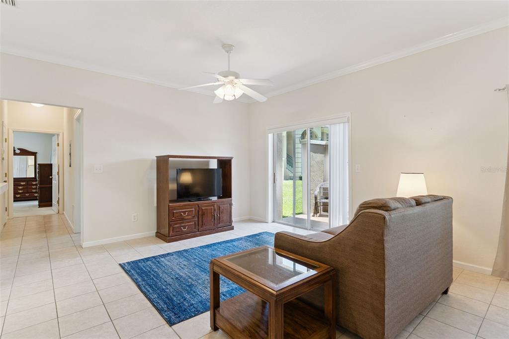 A living room features tile floors, a blue area rug, a sofa, and sliding glass doors — 1502 EAGLE POND DRIVE UNIT 15, WINTER HAVEN, FL