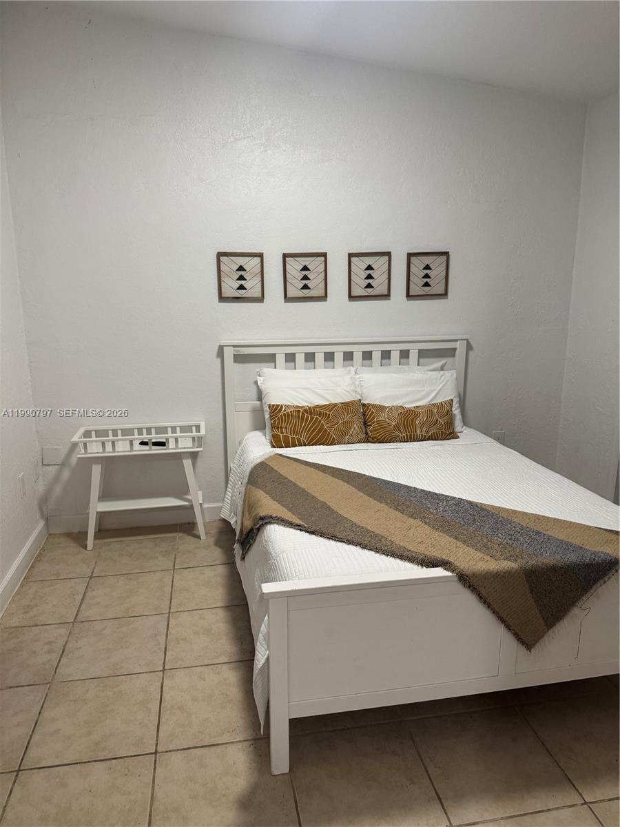 A bedroom features a white bed frame, a small side table, and four wall-mounted pictures — 6126 SW 61st St, South Miami FL 33143, SOUTH MIAMI, FL