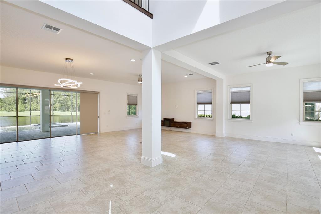 An open-concept living area features light tile flooring, white walls, and a large sliding glass door — 10822 MOBBERLEY CIRCLE, ORLANDO, FL