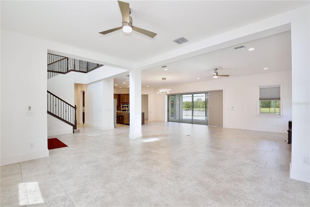 An open-concept living area features light tile flooring, a staircase, and sliding glass doors — 10822 MOBBERLEY CIRCLE, ORLANDO, FL