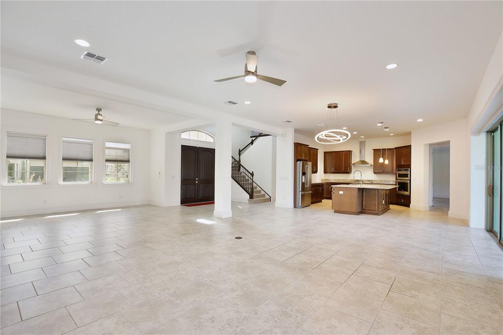 An open-concept living area features tile flooring, a kitchen with an island, and a staircase — 10822 MOBBERLEY CIRCLE, ORLANDO, FL