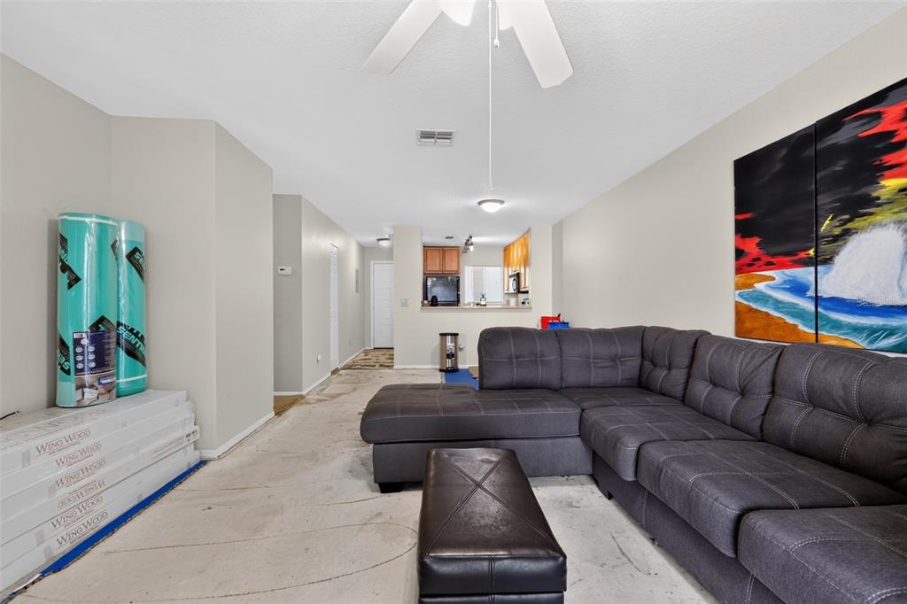 A living room features a gray sectional sofa, an ottoman, and flooring under renovation — 3 ARBOR CLUB DRIVE UNIT 212, PONTE VEDRA BEACH, FL