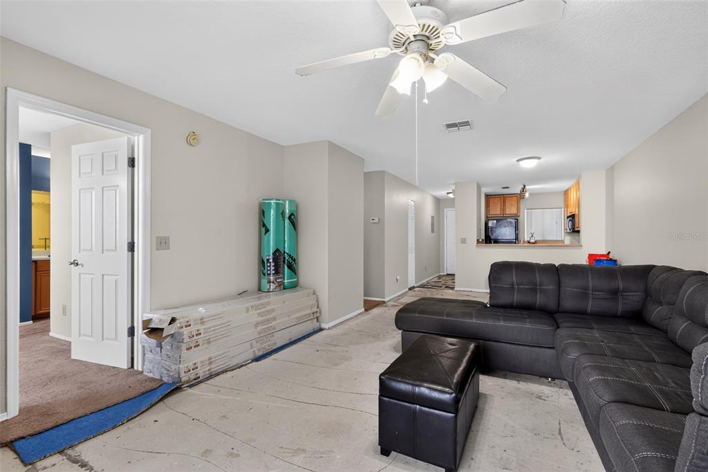 A living room with a ceiling fan, a sectional sofa, and boxes of flooring materials — 3 ARBOR CLUB DRIVE UNIT 212, PONTE VEDRA BEACH, FL