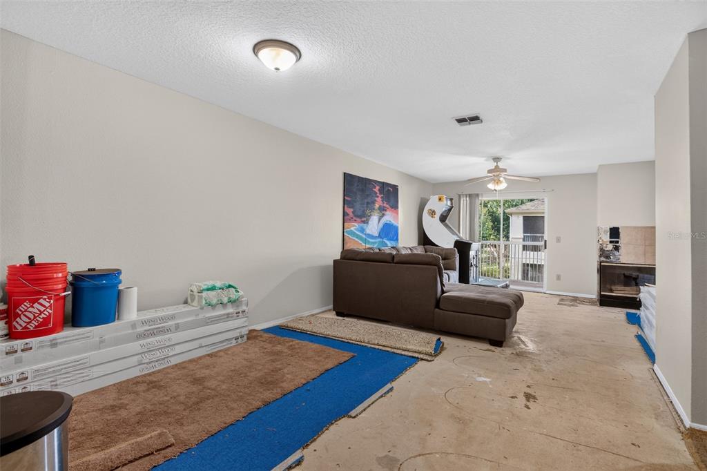 A living room with beige walls, concrete flooring, a brown sectional sofa, and a fireplace — 3 ARBOR CLUB DRIVE UNIT 212, PONTE VEDRA BEACH, FL