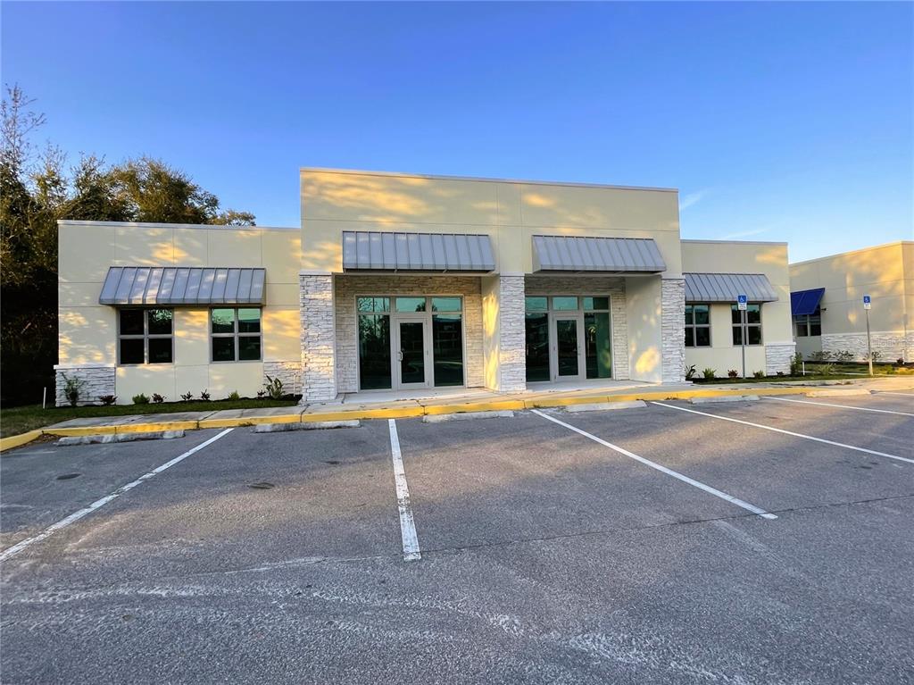 A modern single-story commercial building with a light-colored facade, stone accents, and a paved parking lot — 871 HIGHWAY 466, LADY LAKE, FL