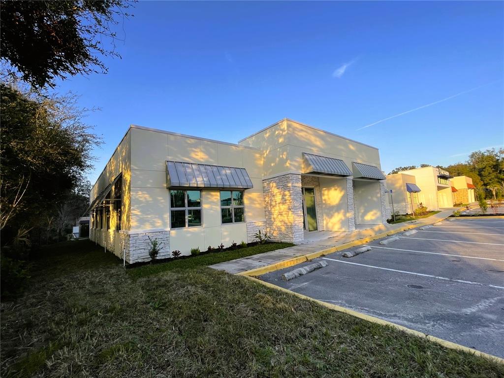 A modern commercial building with light-colored panels, stone accents, and metal awnings over the windows — 871 HIGHWAY 466, LADY LAKE, FL